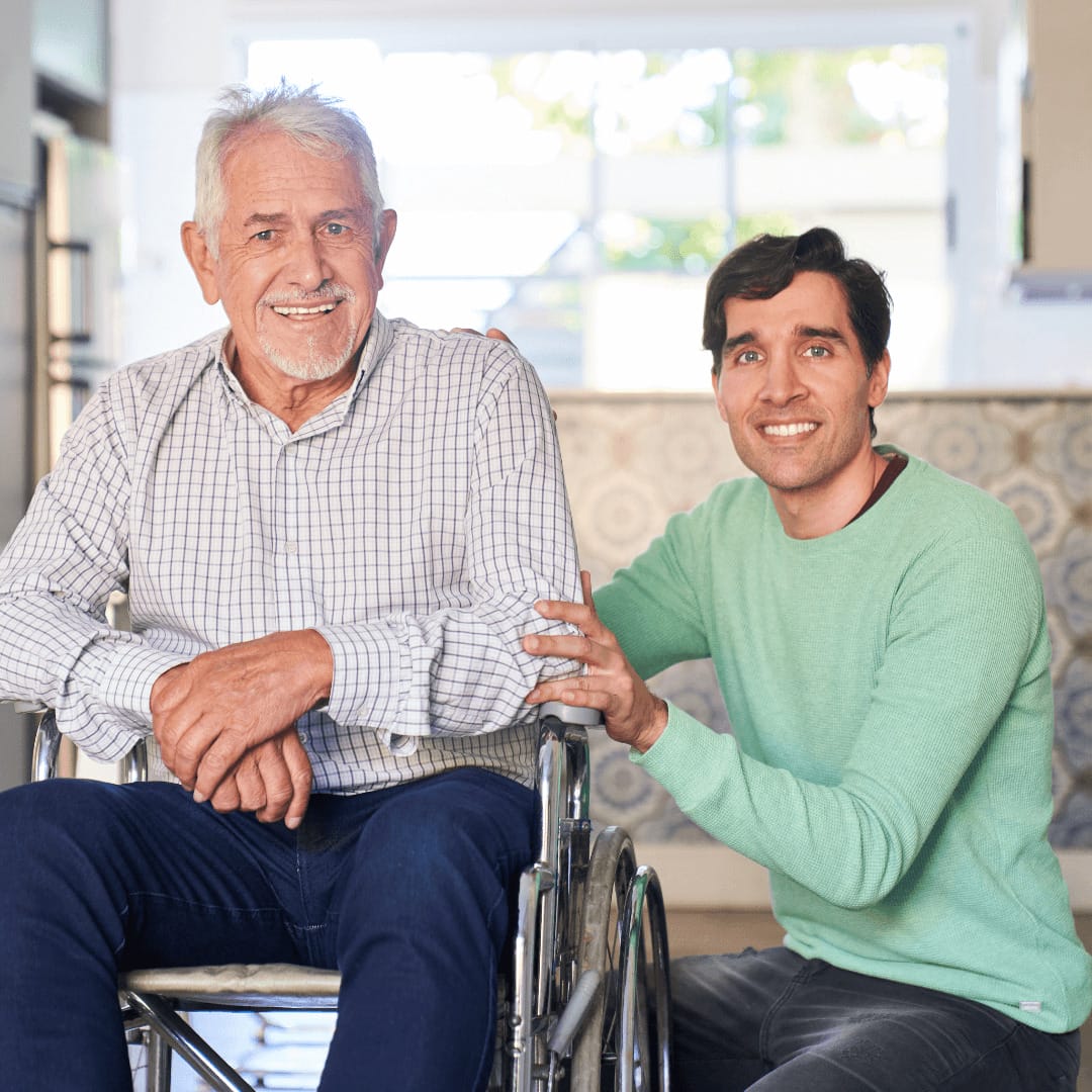 An elderly man in a wheelchair next to a younger man
