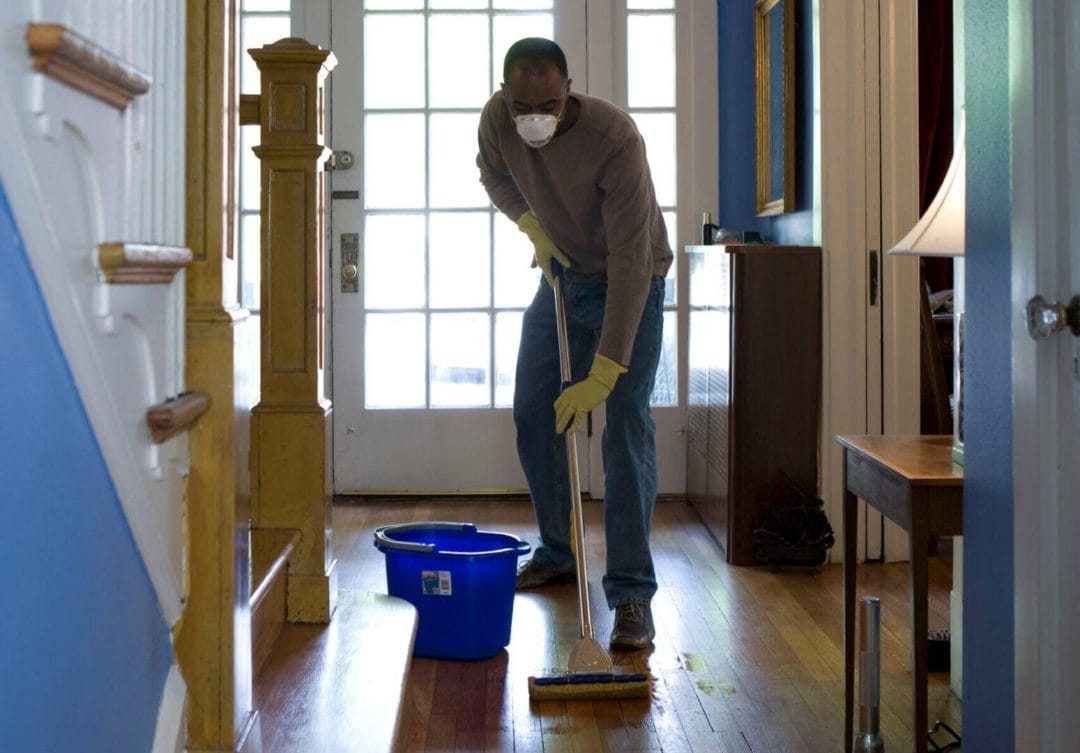 A man mopping the floor of a home's front hallway