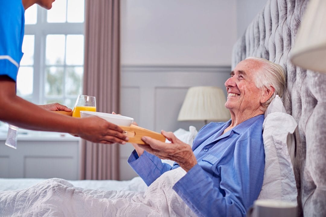FamilyFirst Transition to home, with an elderly man receiving breakfast in bed