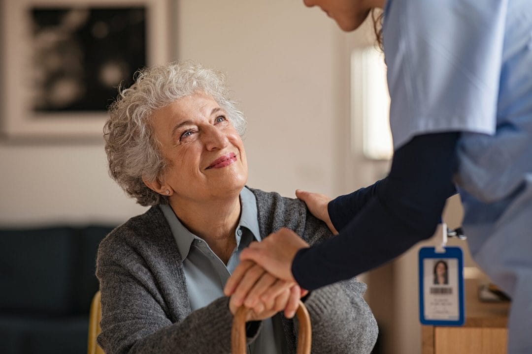 An elder woman is looking at her helpful caregiver