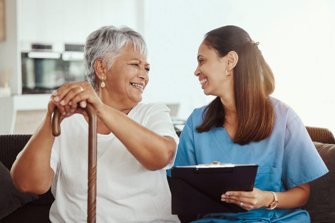 Companion Care - Smiling senior woman with a caregiver who is assisting with paperwork