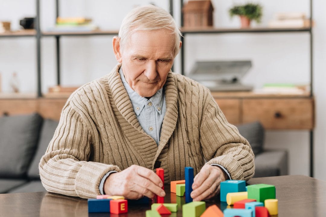 A senior man playing with wooden toys for mental stimulation