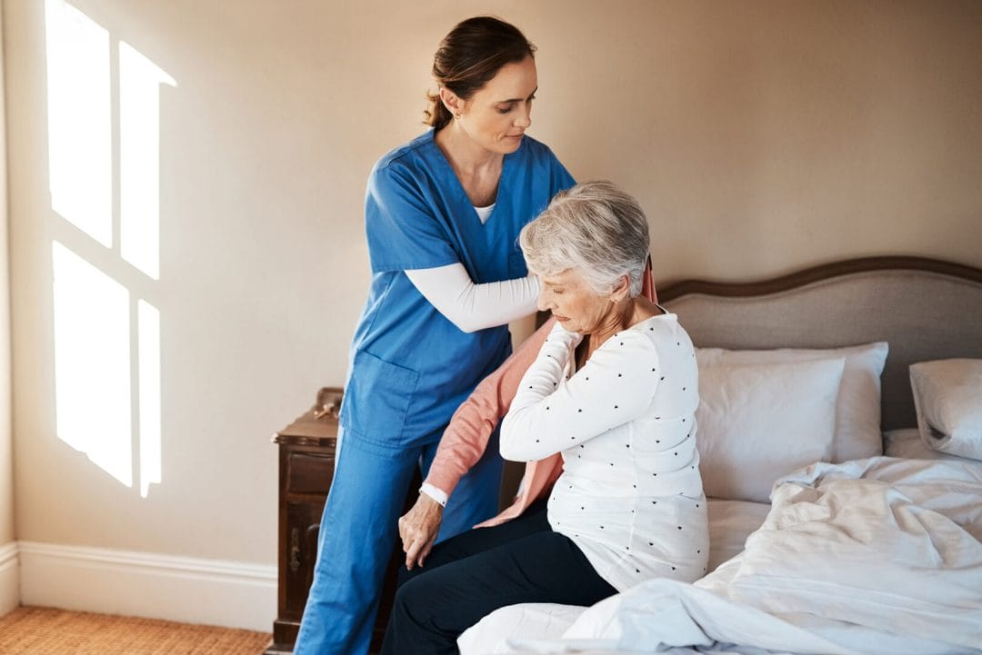 A caregiver helping a senior woman to get dressed